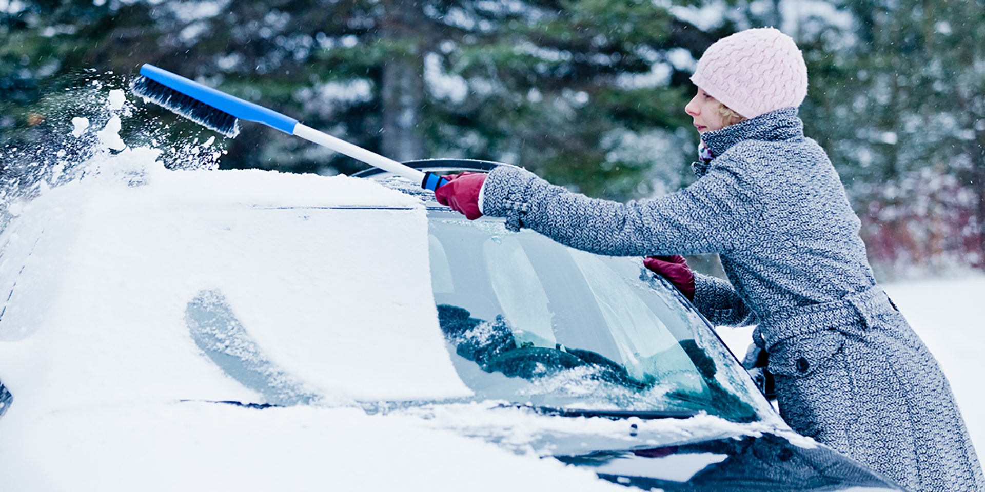 Woman Removing Snow from a Car with a Broom